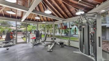 Un gimnasio con equipo de ejercicio, ventanas amplias y vistas al exterior.