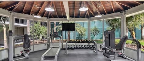 Ett gym med tak, utrustat med löpband, hantlar och styrketräningsmaskiner.