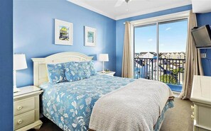 A bedroom with a bed, two bedside tables, a TV, and a balcony with a view. - 2 Belmont Oceanfront Condos Boardwalk Pool Gym (Ocean City)