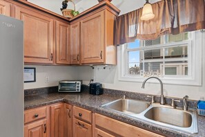 A kitchen with wooden cabinets, a double sink, a toaster, and a refrigerator. - 3 Spacious Dwntwn Condos Bay Views Steps to Boards (Ocean City)