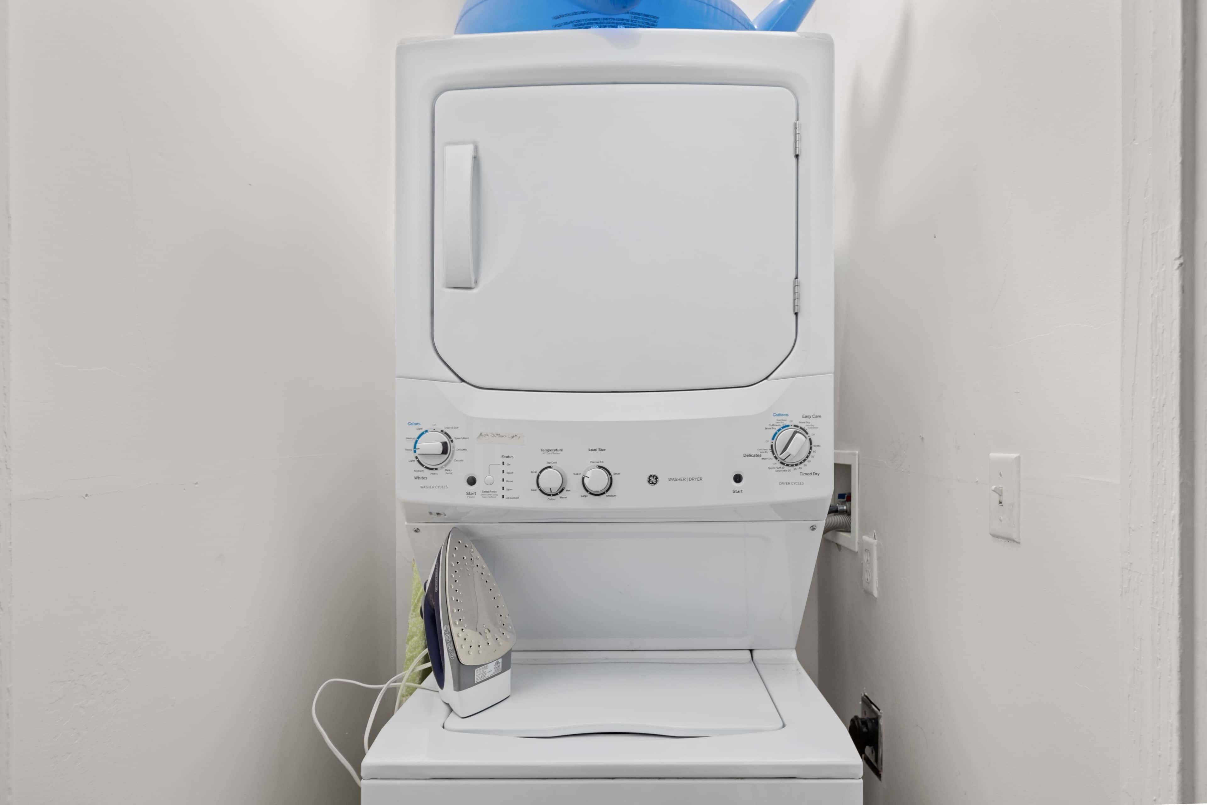 A white washing machine with control knobs and a dryer below it.