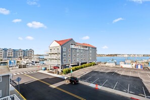 A multi-story hotel with a red roof, located near a marina with boats docked. - 3 Spacious Dwntwn Condos Bay Views Steps to Boards (Ocean City)
