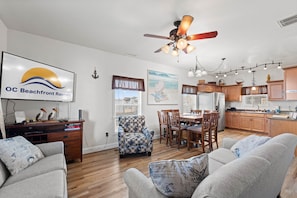 A spacious living room with a ceiling fan, a dining area with wooden chairs, and a kitchen with wooden cabinets. - 3 Spacious Dwntwn Condos Bay Views Steps to Boards (Ocean City)