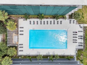An aerial view of a swimming pool with adjacent lounge chairs and a covered area with a green canopy. - 7 min to Disney Luxury Blue King + Pool Parking (Kissimmee)