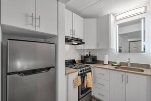 Eine moderne Küche mit einem Edelstahlkühlschrank, einer Mikrowelle, einem Herd und einem Spülbecken.