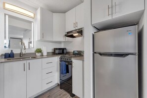 A modern kitchen with white cabinets, stainless steel appliances, a microwave, and a built-in oven. - Whimsical Study 7 min to Disney Pool & FreeParking (Kissimmee)