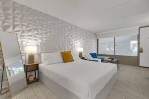 A hotel room with a large bed, two bedside tables, a desk, and a window. - Chic Studio Near Disney World + Free Parking (Kissimmee)