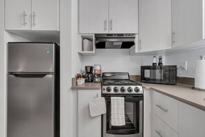 A compact kitchen with a stainless steel refrigerator, a gas stove, a microwave, and a coffee maker. - Cozy Studio 7 mins to Disney + Pool & Free Parking (Kissimmee)