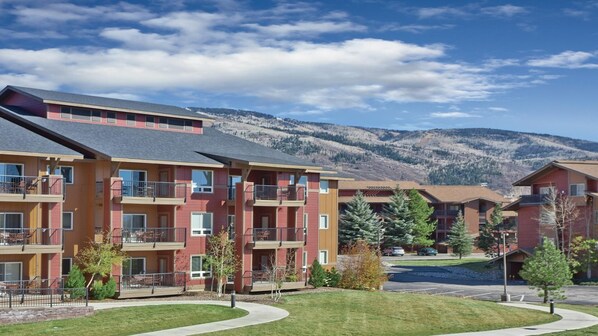 A multi-story hotel with balconies, a parking area, and a mountainous backdrop. - Steamboat 2BR Mountain Villa – Full Kitchen, Fireplace & Near Ski Resort (Steamboat Springs)