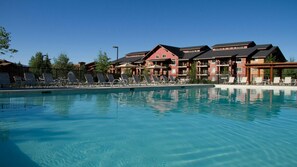 A swimming pool with lounge chairs and a building with multiple balconies in the background. - Steamboat 2BR Mountain Villa – Full Kitchen, Fireplace & Near Ski Resort (Steamboat Springs)