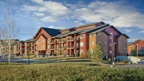 A multi-story residential building with balconies, a parking lot, and a grassy area. - Steamboat 2BR Mountain Villa – Full Kitchen, Fireplace & Near Ski Resort (Steamboat Springs)