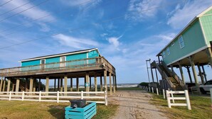 Una propiedad frente al mar con una terraza de madera y un edificio de fachada azul.