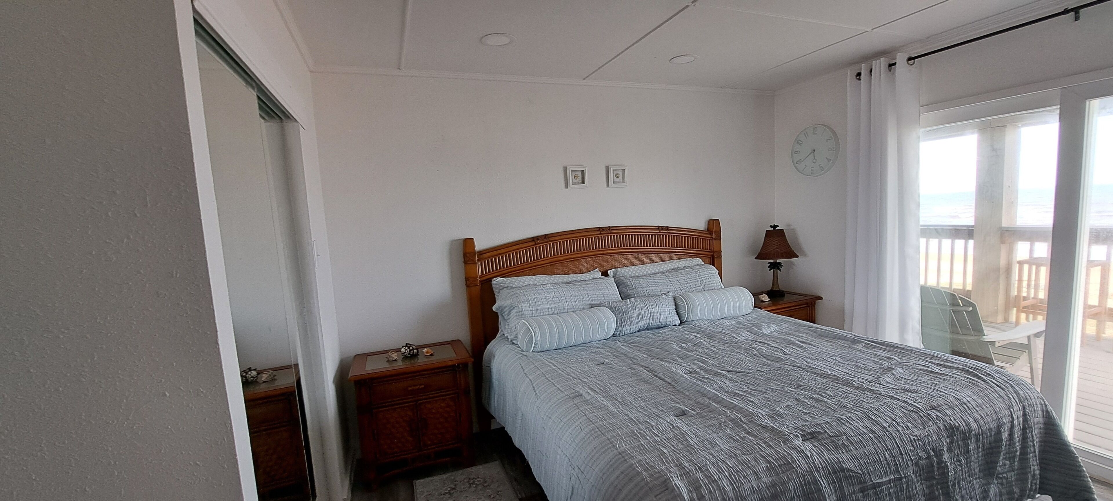 A bedroom with a wooden bed, a nightstand, a lamp, and a clock on the wall.