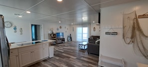A spacious living area with a kitchen, a dining table, and a sofa. - Beachfront House - Sunny Beach Retreat (Gilchrist)