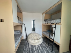 Ein Schlafraum mit zwei Etagenbetten, einem Sitzsack in der Mitte und einem Spiegel an der Wand.