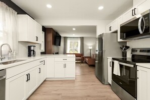 Una cocina moderna con muebles blancos, electrodomésticos de acero inoxidable y suelo de madera.