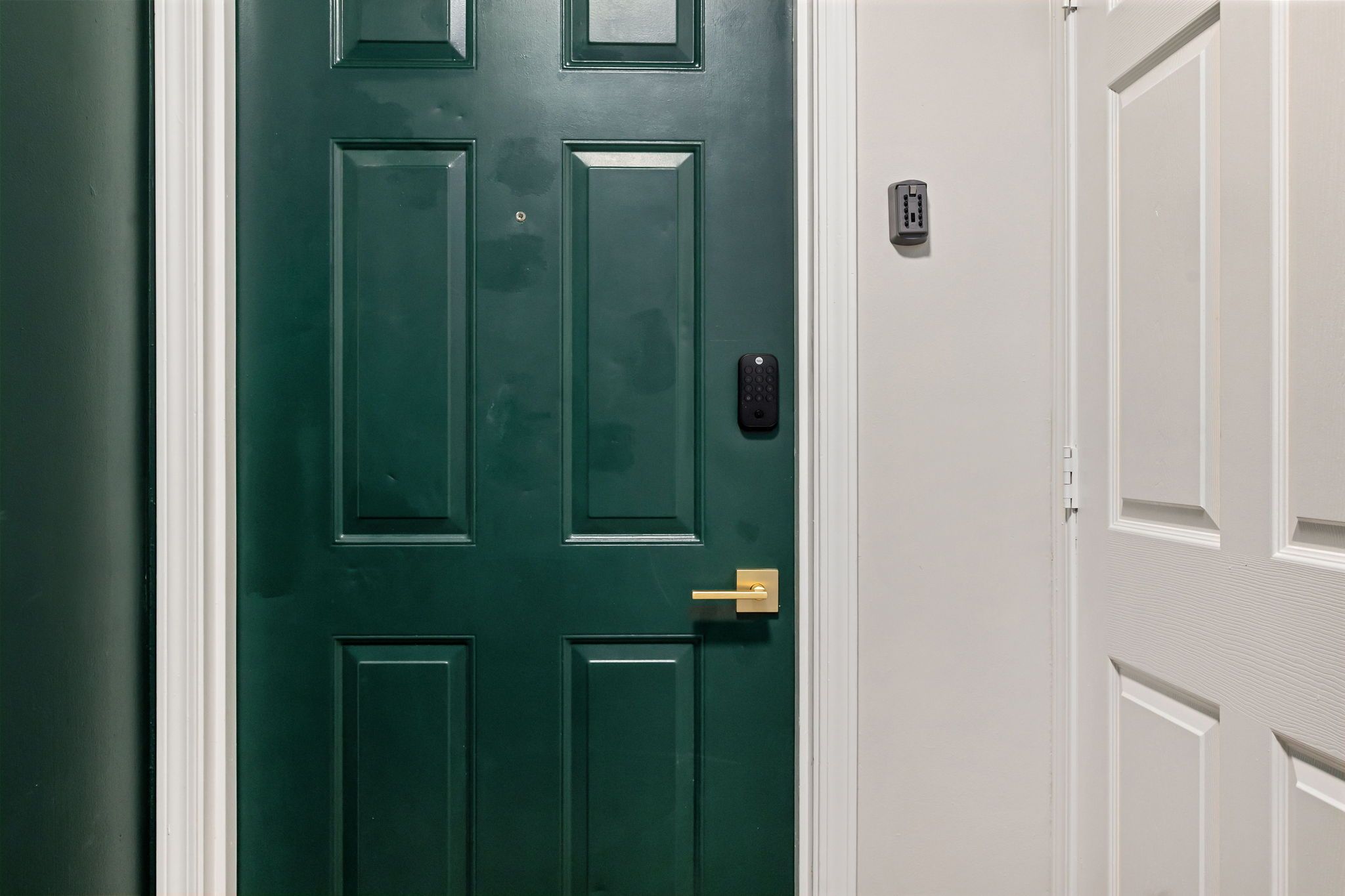 A green door with a keypad lock and a gold handle.