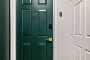 A green door with a keypad lock and a gold handle.