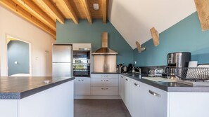 Une cuisine moderne dotée d’un îlot central, d’un four encastré et d’appareils électroménagers en acier inoxydable.