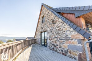 A stone building with a wooden deck and a metal roof. - The Sancy - SAINT SAUVES D'AUVERGNE (SAINT SAUVES D'AUVERGNE)
