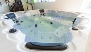 A hot tub with multiple jets, a control panel, and a seating area. - The Sancy - SAINT SAUVES D'AUVERGNE (SAINT SAUVES D'AUVERGNE)