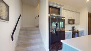 Una cocina con refrigerador, microondas y una escalera.