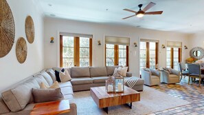A spacious living room with a large sectional sofa, a coffee table, and a ceiling fan. - Hooked on Baytowne | Fisherman’s Village | 2 King Suites + Resort Tram (Miramar Beach)