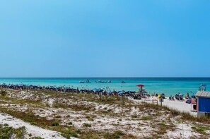 Una playa con una torre de salvavidas, sombrillas y una zona arenosa.