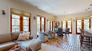 A spacious living area with a sofa, armchairs, a dining table, and a patterned floor. - Hooked on Baytowne | Fisherman’s Village | 2 King Suites + Resort Tram (Miramar Beach)