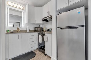 A modern kitchen with white cabinets, a stainless steel refrigerator, a built-in oven, and a microwave. - Elegant King Suite –7 min to Disney & Free Parking (Kissimmee)