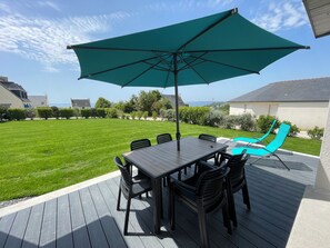 Un patio con tavolo e sedie, un ombrellone verde e una piscina.
