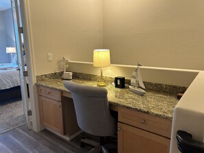 Ein Hotelzimmer mit Schreibtisch, Stuhl, Lampe und einem kleinen dekorativen Segelboot.