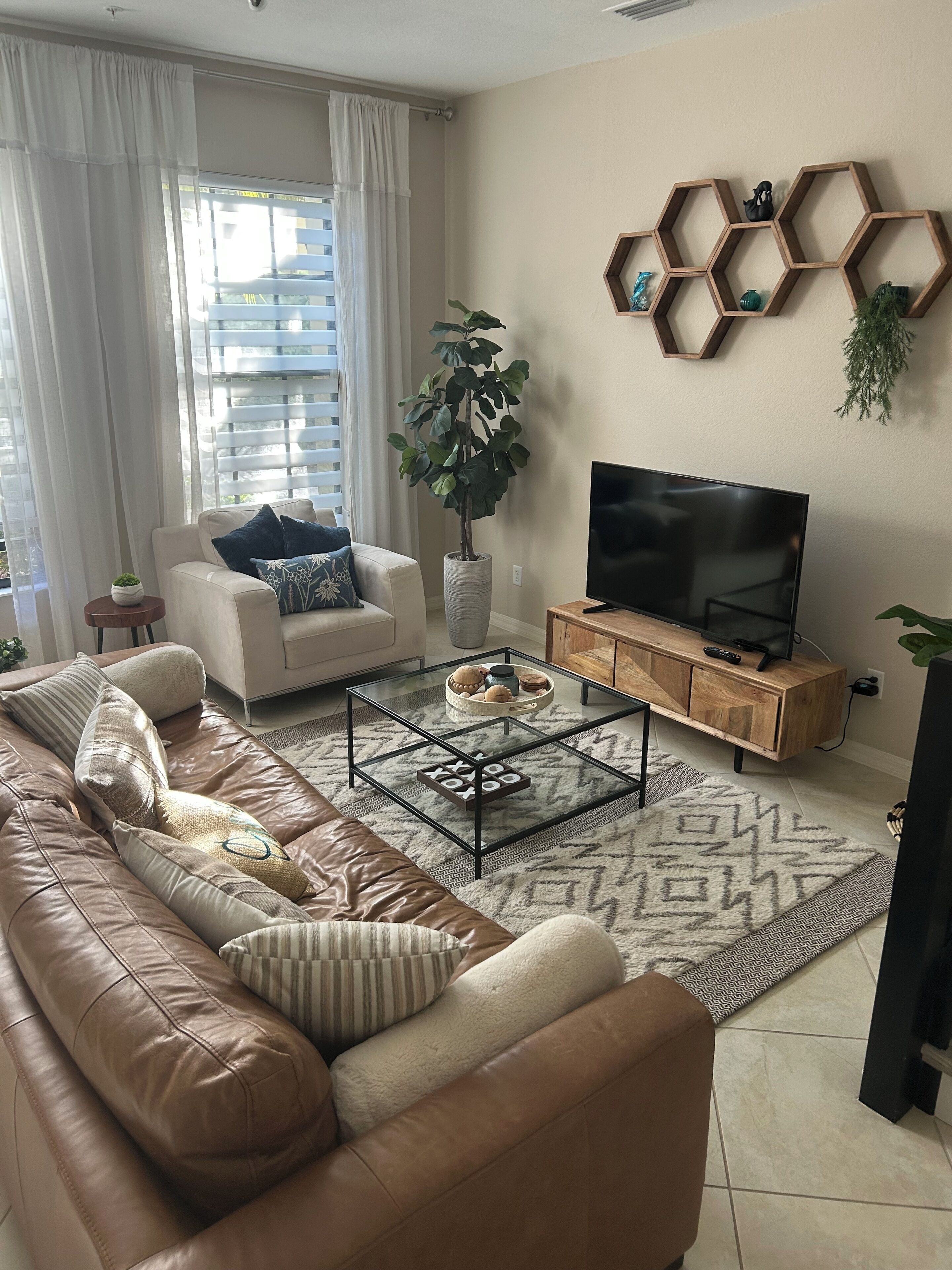 Ein Wohnzimmer mit einer Couch, einem Couchtisch, einem Fernseher und einer Pflanze.