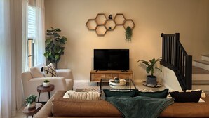A modern living room with a flat-screen TV, a wooden coffee table, a sofa, and a staircase. - OLE’ Lely resort. Beautiful 3-bedroom 2.5 bath townhome. Resort-style living! (Naples)