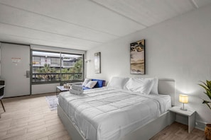 A bedroom with a large bed, a desk, a chair, a window with a view, and a bedside lamp. - Cozy Suite 7 Min to Disney World + Free Parking (Kissimmee)