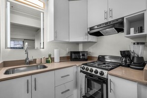 Een moderne keuken met een gasfornuis, magnetron en koffiezetapparaat.
