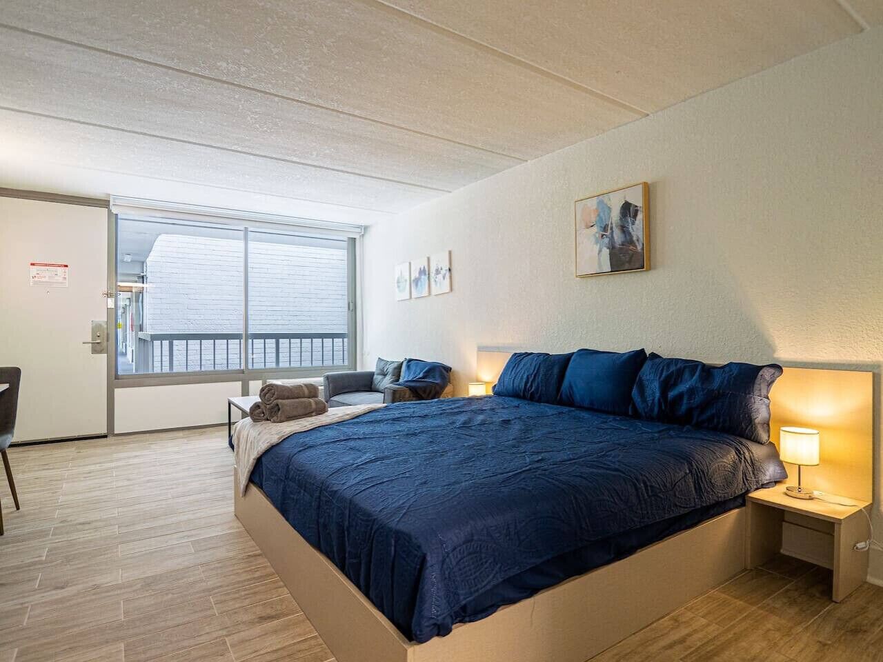 Une chambre à coucher avec un grand lit, des tables de chevet, une chaise et une fenêtre.