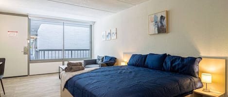 Une chambre à coucher avec un grand lit, des tables de chevet, une chaise et une fenêtre.