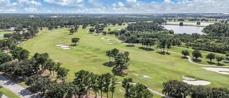 Ein Golfplatz mit Sandbunkern, Bäumen und blauem Himmel.