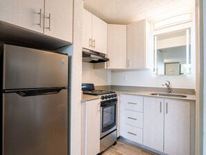 A compact kitchen with a stainless steel refrigerator, a stove, oven, and a sink. - Marvelous Apt 7 Min to Disney + Free Parking | Orl (Kissimmee)