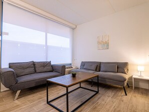 A modern living room with two grey sofas, a wooden coffee table, and a small side table with a lamp. - Marvelous Apt 7 Min to Disney + Free Parking | Orl (Kissimmee)