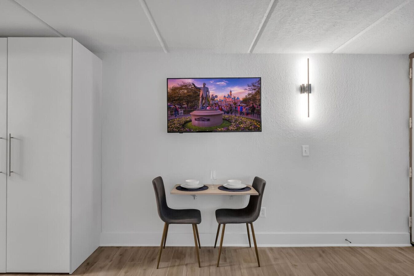 Un coin repas avec une table et des chaises, un tableau accroché au mur et une armoire blanche.