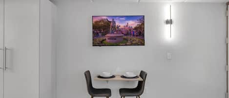 Un coin repas avec une table et des chaises, un tableau accroché au mur et une armoire blanche.