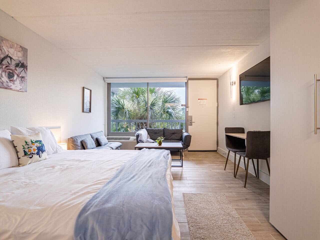 A modern bedroom with a large bed, a sofa, and a desk area.