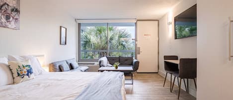 A modern bedroom with a large bed, a sofa, and a desk area.