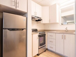 A compact kitchen with a stainless steel refrigerator, a built-in oven, and light-colored cabinetry. - Bright Studio 7 Min to Disney World + Park | Orl (Kissimmee)