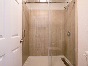 A glass-enclosed shower stall with a wooden floor and a white door. - Bright Studio 7 Min to Disney World + Park | Orl (Kissimmee)