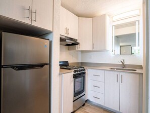 A compact kitchen with a stainless steel refrigerator, a gas stove, and a built-in oven. - Bright Apt 7 Mins to Disney + Free Parking & Pool (Kissimmee)