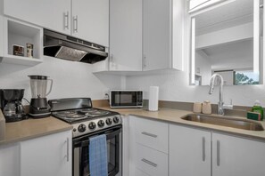 Eine moderne Küche mit Gaskochfeld, Mikrowelle und Kaffeemaschine.