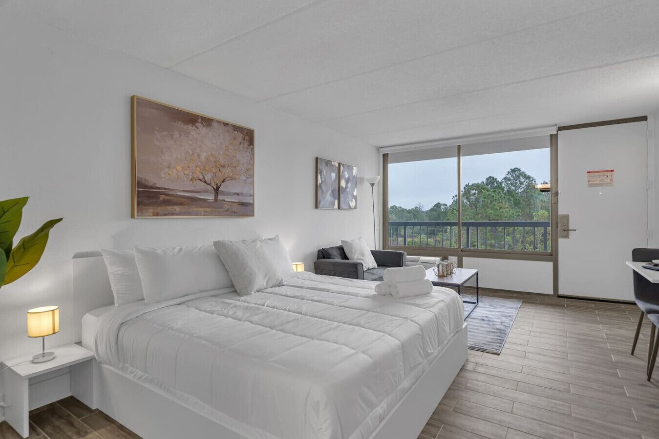 Una camera d'albergo con un letto grande, una scrivania, una sedia e un balcone con vista.